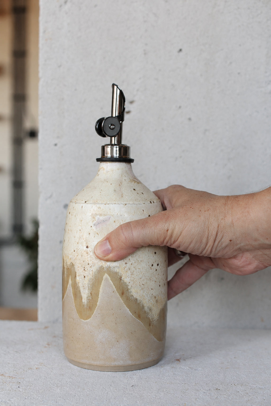 Ceramic oil bottle in light sand